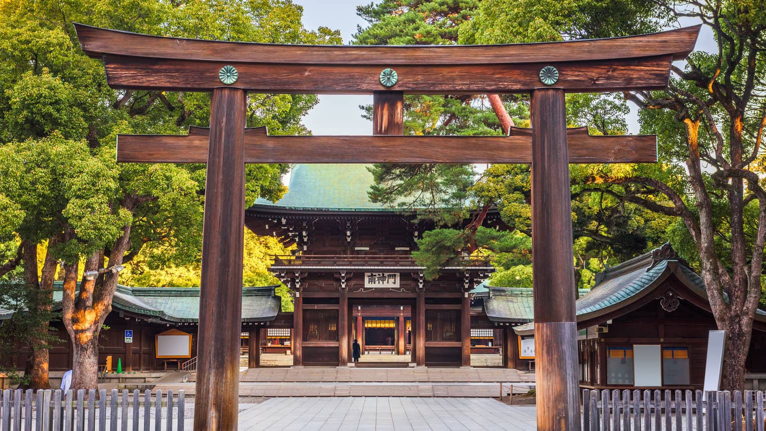 View through the entrance gate to the cypress wood and copper-roofed Meiji Shrine and grounds set amidst numerous lush trees.