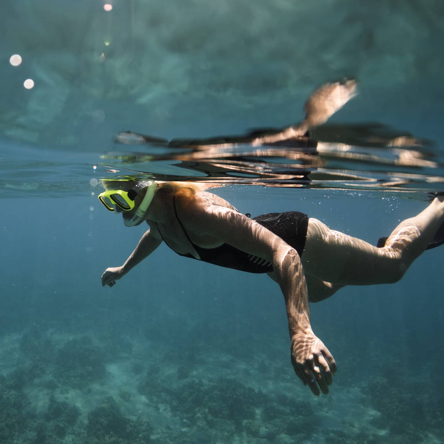 Underwater view of woman with snorkel, mask over coral reef