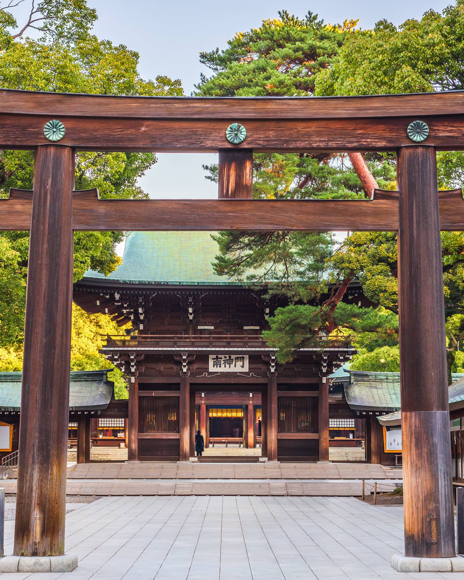 View through the entrance gate to the cypress wood and copper-roofed Meiji Shrine and grounds set amidst numerous lush trees.